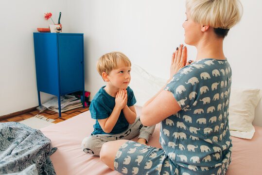 Mother and her 5 years old kid meditating in bed