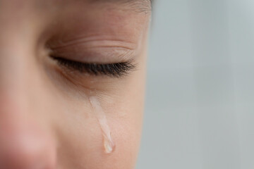 Close up image of teardrop rolls down the boy's cheek, his eyes are closed, he is upset and crying....