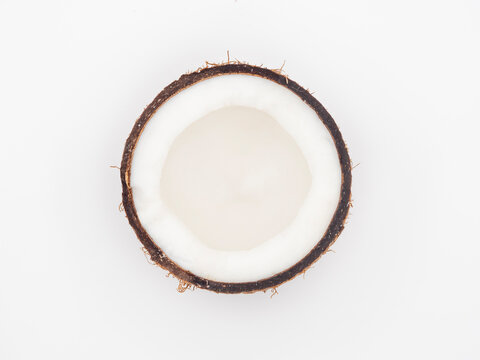 Half a coconut with fresh flesh and peel isolated on a white background.