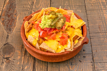 Amazing Mexican guacamole nachos recipe in clay pot with melted cheddar cheese and jalapenos