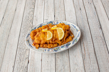 Breaded chicken breast fillets with lemon slices on a plate decorated with Chinese motifs