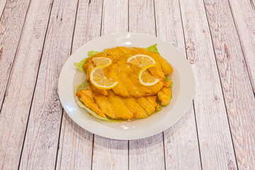 Breaded chicken fillets flooded with Chinese-style lemon sauce in a restaurant