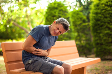 Man with stomach pain outdoor. Healthcare and medicine concept
