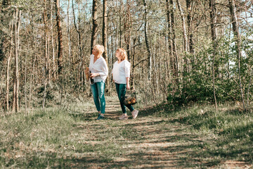 Two female friends mature are walking through the forest. Active lifestyle, hobby