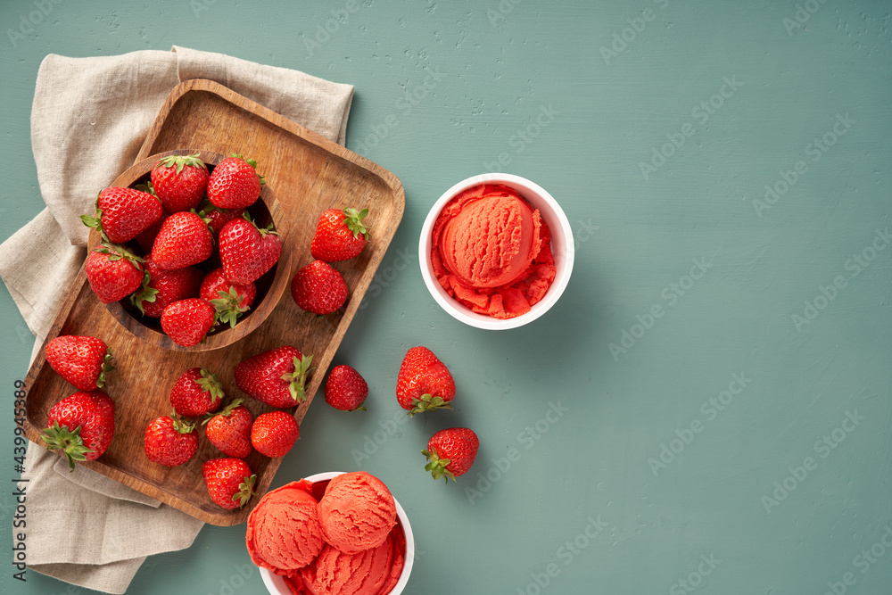 Poster Strawberry sorbet with strawberries on blue background with copy space. Heap of strawberry with ice cream in ice cream paper cups.