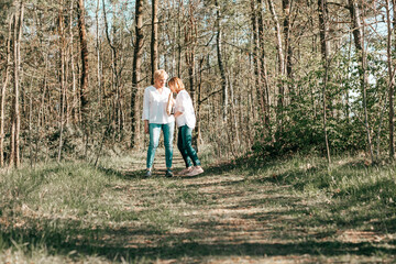 Fototapeta premium Two female friends mature are walking through the forest. Active lifestyle, hobby
