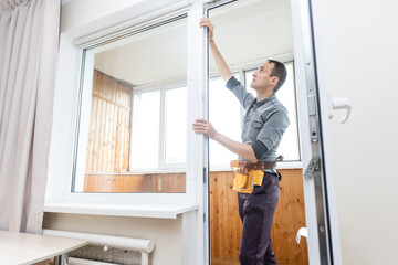 Construction worker removing sticky tape from window frame in house