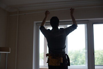 A handyman installing new cornice for curtains, home repair and renovation works © Angelov