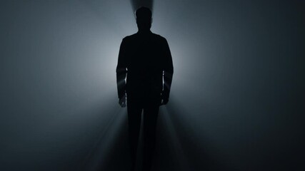 Silhouette man walking in darkness. Male person going straight on in dark. - Powered by Adobe