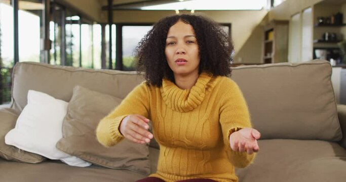 Happy Mixed Race Woman Sitting On Couch In Living Room, Talking And Smiling During Video Call