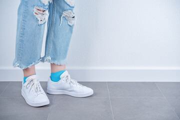 Women's feet in white sneakers on a white background