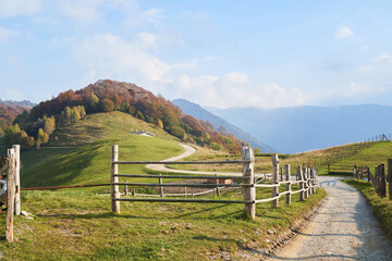 Picturesque Alps autumn landscape, wooden fence and mountain hills in Lombardy, Italy. Tourist adventure, colorful autumn scene
