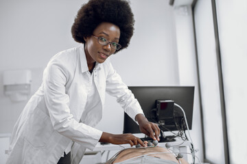 Close up portrait of young pleasant Afro American woman doctor gp cardiologist, sticking ECG...