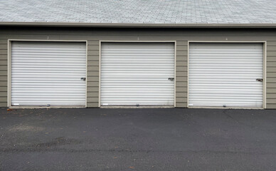 White garage doors with numbers on buildings with tan siding