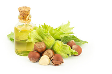 Glass bottle of hazelnut oil isolated on white background with green fresh hazelnuts