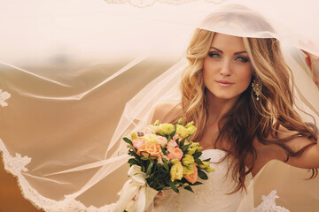 Beautiful blonde bride with bouquet of pink flowers outdoor. Portrait of the bride. Beautiful...