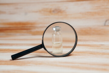magnifier and bottle on the table. vaccine search concept.