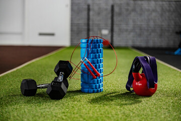 Fitness lifestyle and equipment. Sports equipment on artificial green grass in the gym - roller,...