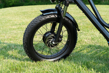 Wheel of the electric bicycle view from side. E bike motor in the park grass of the city....