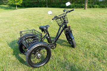Electric trike or bicycle in the park in sunny summer day. Unfiltered, with natural lighting. E motor and power battery of the three wheel bike. Ecology and green energy concept. Ev – electric vehicle - obrazy, fototapety, plakaty