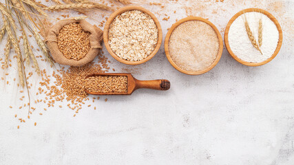  Wheat grains , brown wheat flour and white wheat flour in wooden bowl set up on white concrete background.