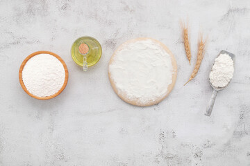 The ingredients for homemade pizza dough with wheat ears ,wheat flour and wheat grains set up on white concrete background.