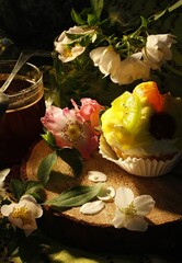 Dessert with vanilla cream and fruit in a paper basket. Wooden mat, a cup of black coffee and rose hips for decoration