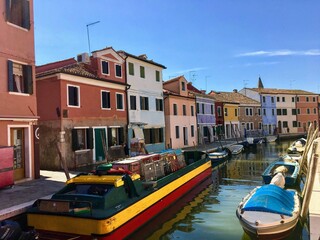 Fototapeta na wymiar A beautiful view of the famous canals and colourful homes of the island town of Burano, Italy on a beautiful morning. A popular tourist spot known for lace making.