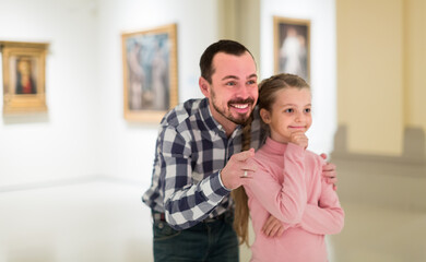 attractive father and daughter exploring expositions in museum halls