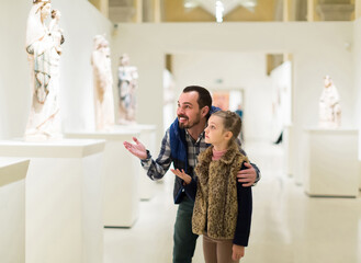 young english father and daughter looking at ancient bas-reliefs in museum