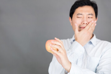 A man with a toothache looks at an apple that wants to eat