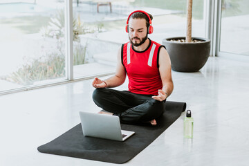Young latin man with red headphones listening to a guided meditation to relax in yoga session on...