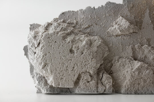 Battered, destruction concept image. A piece of crumbling, but standing piece of dry wall (or masonary) on neutral white background with natural shadows.