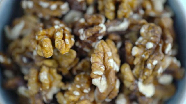 Walnuts Rotating In Bowl. Close-Up Macro 4K Shot of Nuts Spinning. Nuts And Food On White Background. Protein Plant Based Raw Vegan Food. Health And Vegetarian Foods. Healthy Breakfast Ingredients.