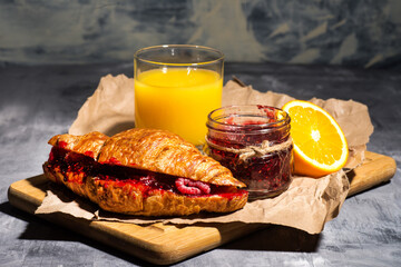 orange juice and croissant with raspberry jam.