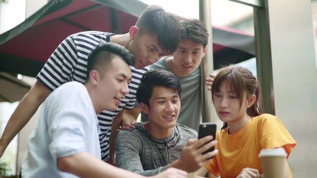 group of young asian adults relaxing in outdoor coffee shop