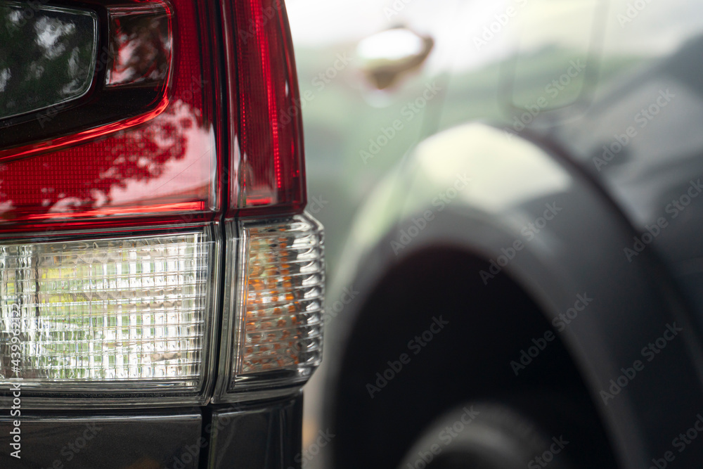 Wall mural Close-up trail light of car in parking lot with blurred of other car.