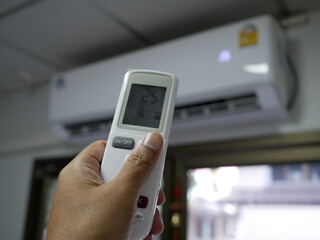 closeup of hand using remote control air conditioner.