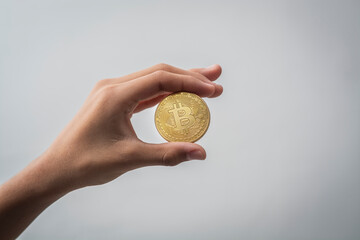HAND HOLDING BITCOIN COIN ON WHITE BACKGROUND