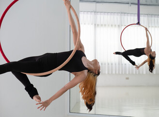 Young beautiful Asian dancer dressed in black color performing aerial dance with aerial hoop at the studio..