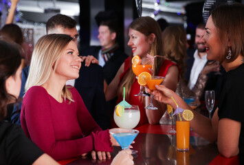 Cheerful girl with best friends partying in bar, dancing and toasting drinks