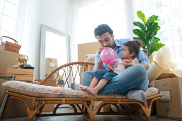 Father and daughter blowing up balloons, having fun together, little girl play balloon with her...
