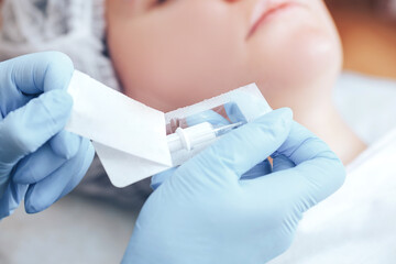 The permanent makeup artist openning a sterile new cartridge clipper, needle to make the procedure...