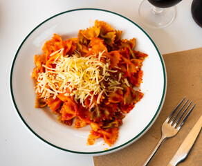 Spanish traditional cuisine Lazos con tomate, pasta with cheese on a white plate