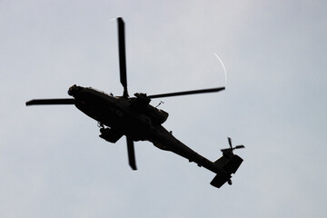 Apache army attack helicopter in flight from below with rotor vortices