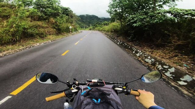 Vietnam road trip travelling mountain winding road on bends in misty valley scenery.
Point of view video from behind the rider of a motorbike, motorcycle or scooter on a street or rural road, Vietnam