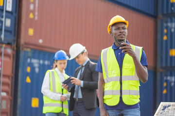 Builder Engineering in hardhat with radio communication over group of builders at construction site.