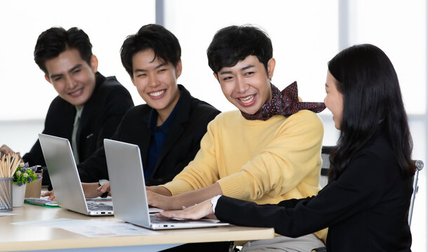 A group of multi-sex colleagues businesspeople, tomboy and transgender gay, working together with happy and intimate manner with laptop notebook computer in office