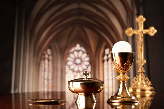 First Holy Communion. Catholic religion theme. Crucifix, the Cross and Golden chalice and wafer on the altar in the church.