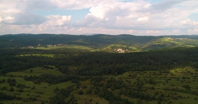 Aerial view of sunlit forest, fields and villages in Slovenia - tracking, drone shot